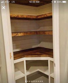 an empty corner in a closet with wood flooring and white painted shelvings