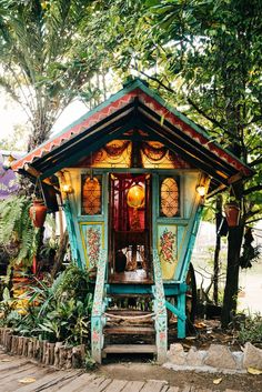 a small colorful building sitting in the middle of a forest