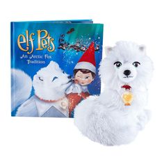 a white stuffed animal next to an elf's book with the title, arctic fox tradition