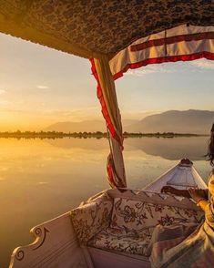 a woman is sitting in a boat on the water at sunset with her head turned to the side