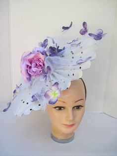 "* This pleated polka dot hat base has a 14\" diameter and has an overlay of shredded white horsehair with purple Hydrangea petals scattered about. In the center are two pink silk roses with purple highlights. * On a satin covered acrylic headband it is secure, well balanced and comfortable to wear for extended periods of time. * Upon ordering you will receive this exact headpiece. * Perfect for this Season's Derby events, ladies luncheon and gatherings, fashion show, wedding, wedding shower or White Floral Headpieces For Spring, White Flower Hat For Royal Ascot, White Fascinator For Spring Races, Spring White Fascinator For Races, White Spring Races Fascinator, White Flower Fascinator For Spring, White Fitted Flower Hats, Fitted White Flower Hats, Whimsical White Fascinator For Royal Ascot