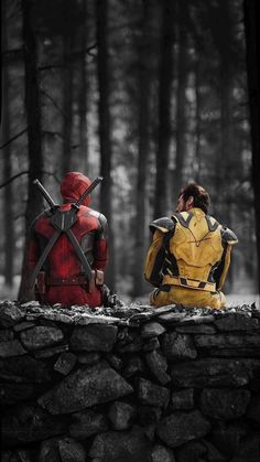 two people dressed as deadpools sit on a stone wall in the woods with swords