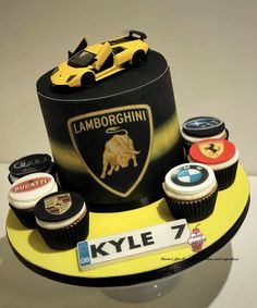 a cake with cupcakes and sports cars on the top is decorated to look like a lamb logo