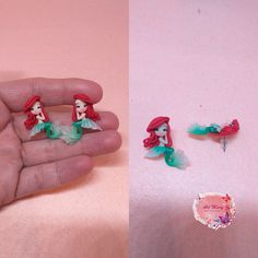 the little mermaid earrings are being held by someone's hand and they have been made from plastic