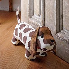 a brown and white stuffed dog sitting on top of a wooden floor next to a door