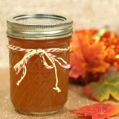 a jar filled with liquid sitting on top of a table next to leaves and flowers