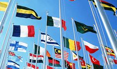 many different flags are flying in the wind on a sunny day with blue sky behind them