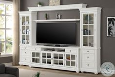 a white entertainment center with glass doors and drawers in a living room next to a gray wall