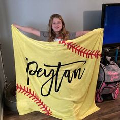 a girl holding up a yellow blanket with the word pelotan written on it