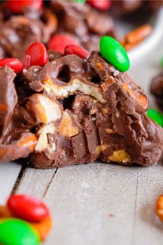 a chocolate candy bar with m & m candies on it's side and some nuts in the background