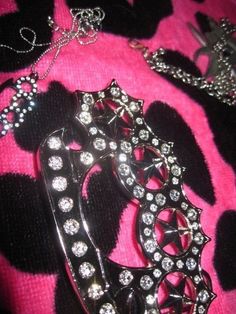 a close up of a brooch on a pink and black blanket with other items