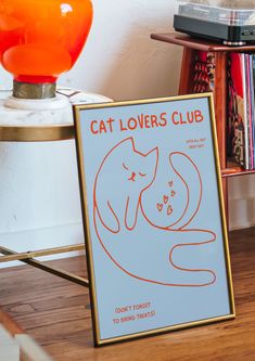 a cat lover's club poster sitting on top of a table next to a lamp