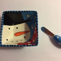 a blue and white plate with a snowman design on it next to a brush