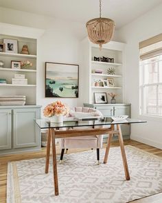 a glass table in the middle of a room with shelves on either side and a chandelier hanging from the ceiling