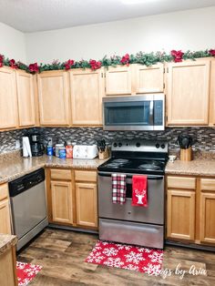 a kitchen decorated for christmas with red and white decorations on the counter top, silver appliances and stainless steel dishwasher