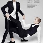 two people in black and white outfits posing for a magazine cover with one holding the other's leg