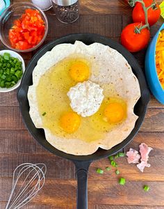 eggs are being cooked in a skillet on a table with other ingredients and utensils