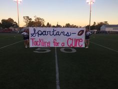 two cheerleaders holding a sign on the field