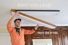 a man holding up a piece of wood above his head with the words remove cover and bulbs above him