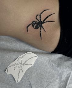 a black spider tattoo on the back of a woman's neck and shoulder,