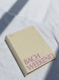 a book sitting on top of a white sheet covered in pink lettering that reads bach weekend