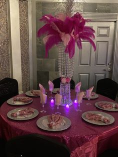 the table is set with pink and silver plates, place settings, and a tall centerpiece