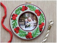 a christmas ornament with red flowers and green leaves on it next to a rope