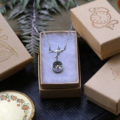 an open box with a necklace in it on a table next to other jewelry items