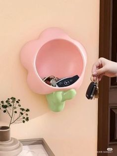 a pink flower shaped shelf with keys in it and a hand holding the key chain