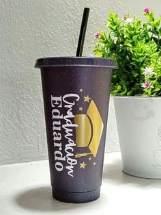 a cup with a straw in it sitting next to a potted plant