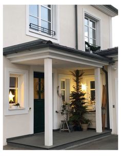 the front entrance of a white house with green door and window sill at night