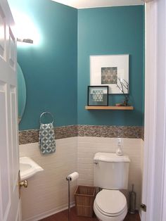 a small bathroom with blue walls and white fixtures on the wall, including a toilet