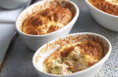 four white bowls filled with food on top of a table