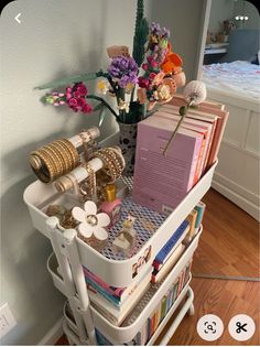 a white cart filled with lots of books and other items on top of a hard wood floor