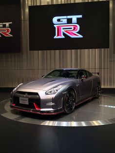 a silver sports car on display in front of a sign that says gtr r