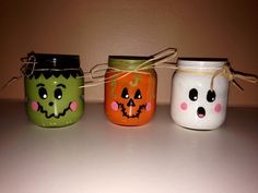 three painted mason jars with faces on them