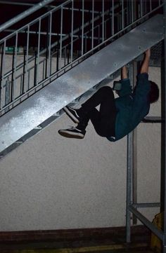 a man riding a skateboard down the side of a metal hand rail on top of a stair case