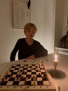 a young boy playing chess in front of a lit candle