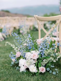 a bouquet of flowers sitting on top of a wooden chair in the middle of a field