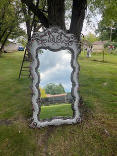 a mirror sitting in the grass next to a tree