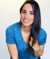 a woman with long dark hair is smiling at the camera while wearing a blue shirt