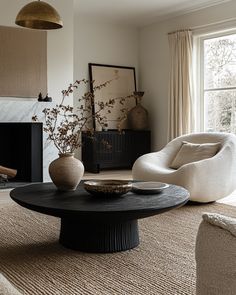 a living room with two chairs and a table in front of a fire place on the floor