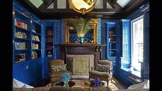 a living room filled with furniture and a fire place in the middle of blue walls