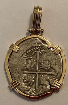 a gold pendant with an image of a cross and two people in the center, on a white background