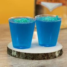 two glasses filled with blue liquid sitting on top of a table