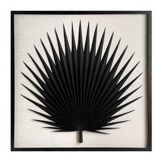 a black and white paper sculpture in a frame on the wall, depicting a palm leaf