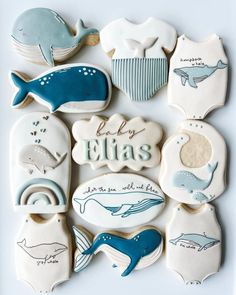 some cookies are decorated with blue and white sea animals, whale tails, and baby names