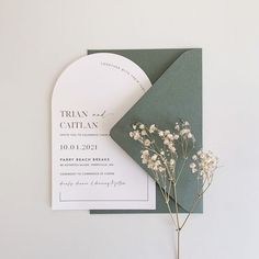 the wedding stationery is laid out on top of an envelope with flowers in it