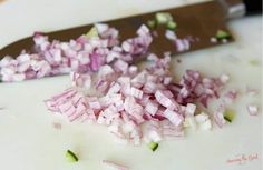 chopped red onions on a cutting board next to a knife