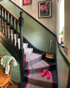 there is a stair case with pink shoes on the bottom and green walls behind it